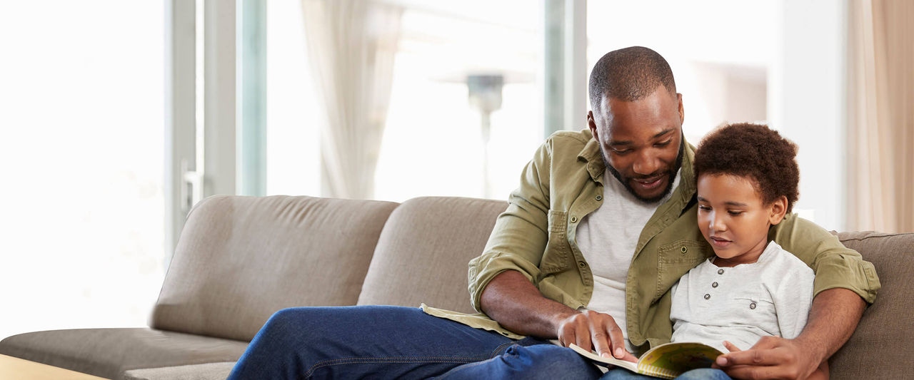 Dad reading a book to son on the couch