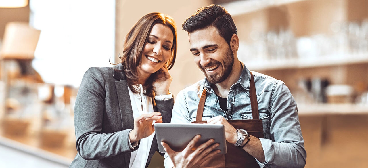 Waiter and lady looking at a laptop and laughing