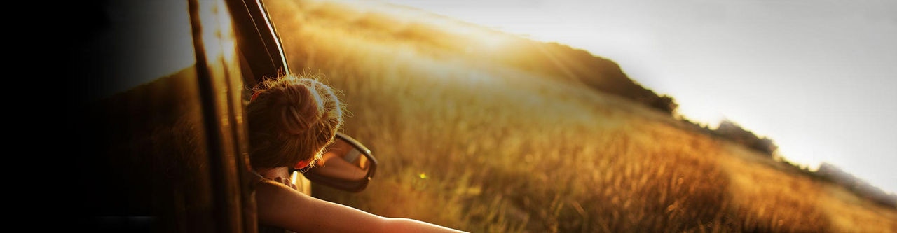 Girl with her hand out of the vehicle watching the sunset