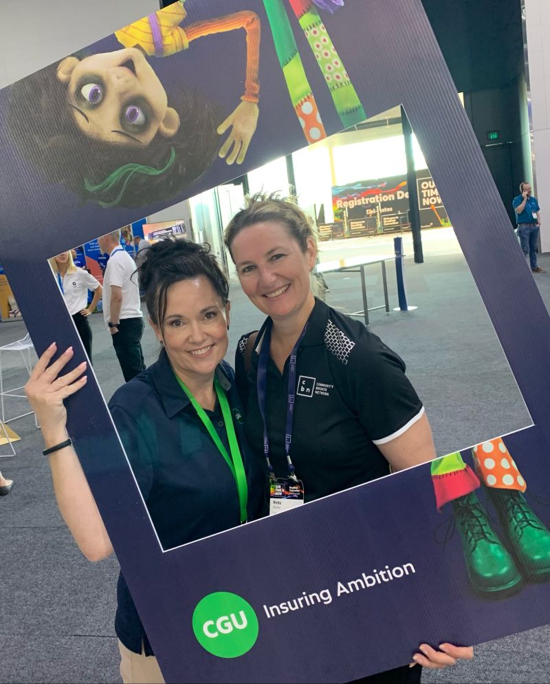 Two ladies smiling by the event registration desk