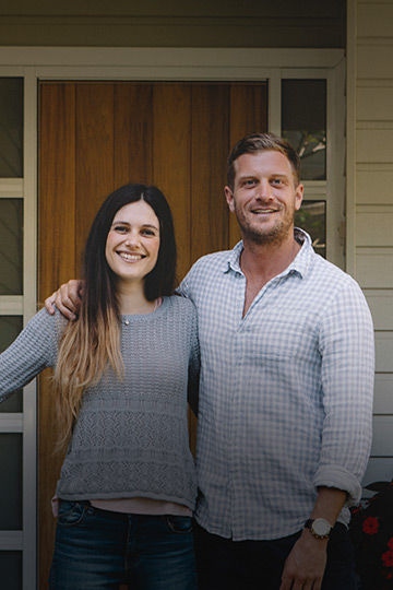 Young couple smiling while standing at their front yard