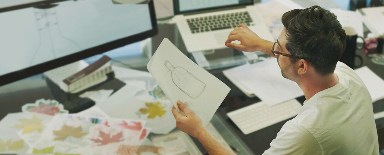 Guy looking at sketch drawing of bottle